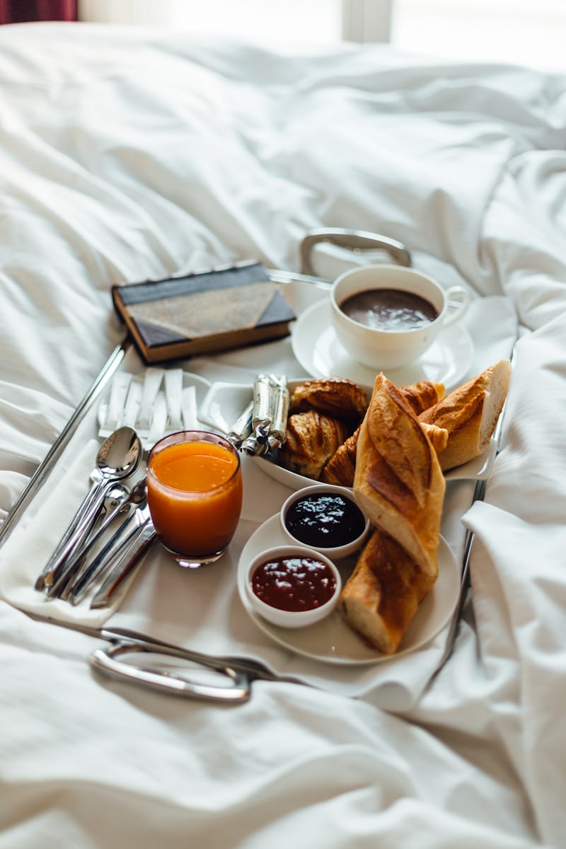 Desayuno boutique servido sobre cama blanca